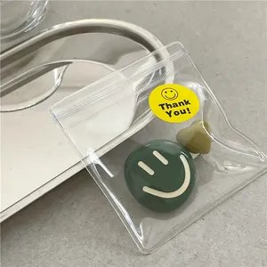 Detailed view of cute green smiley badge and heart accessory in clear zipper bag