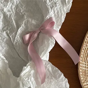 Detail of light pink satin bow hair clip with long ribbons on artistic background