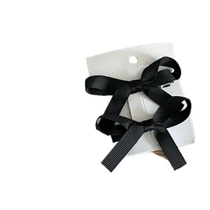Pair of elegant black grosgrain ribbon bow hair clips on a white display card
