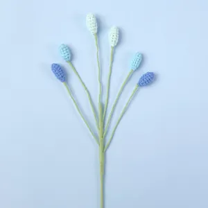 Handgefertigter Häkelrosenzweig mit sechs blau abgestuften Strickblumen an einem Stiel