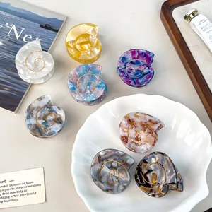 Acetate shell hair claws with marble texture and gold spiral details in a ceramic tray
