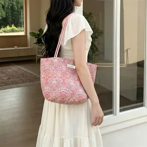 Détail du sac bandoulière rose à fleurs avec étiquette de marque et fine lanière