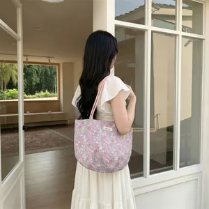 Détail du petit motif floral et de la poignée rose sur un sac cabas en toile mauve