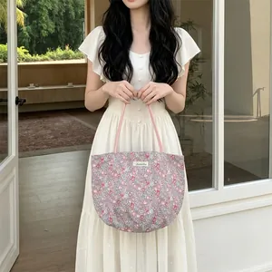 Vue détaillée du sac cabas en toile fleurie avec anses roses et étiquette logo