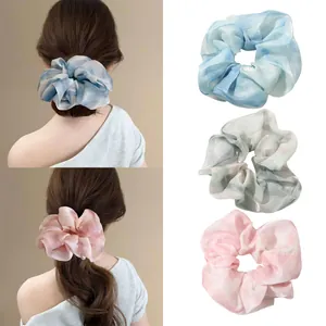 Detailed view of oversized satin scrunchies in gradient blue, green and pink shades