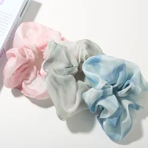 Macro view of satin scrunchies in pastel pink, green, and blue with marble texture