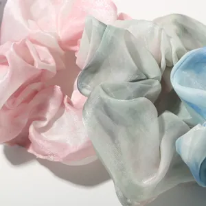 Close-up of pastel gradient organza scrunchies in pink, green, and blue silky fabric