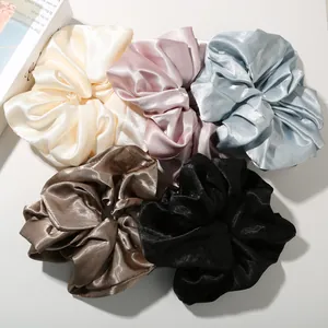 Close-up of five colorful satin hair scrunchies with soft silk texture and glossy finish