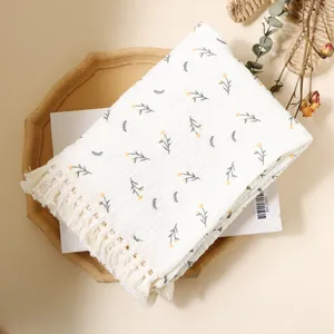 Macro shot of double-layer cotton baby blanket featuring yellow floral print and tassel edges
