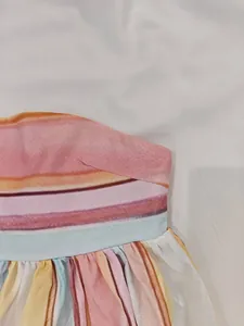 Detail of colorful striped off-shoulder dress with elegant pleated waist design