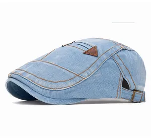 Détail de la casquette plate en jean bleu clair avec coutures marron et boucle en métal