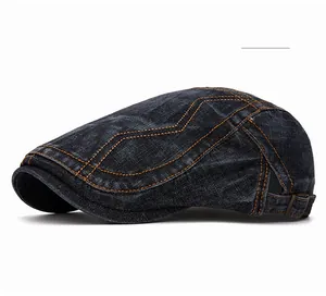Détail d'une casquette plate en jean noir avec surpiqûres orange et boucle métallique