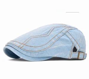 Détail de la casquette gavroche en jean bleu clair avec coutures orange et boucle réglable