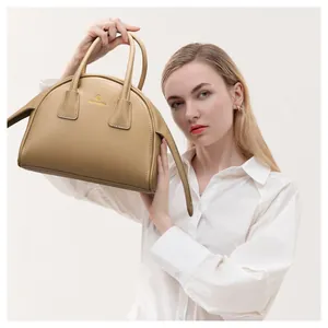 Detail van de beige handtas met gouden merklogo en de gladde leertextuur