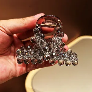 Macro detail of large hair claw clip with grey faceted crystals and brown acrylic base