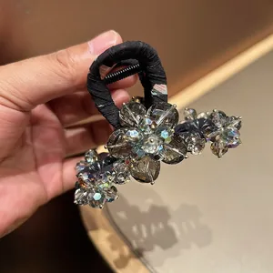 Close-up of floral hair claw clip featuring grey crystals and black fabric wrap