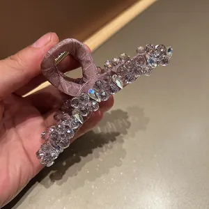 Macro detail of large Korean hair claw clip featuring purple crystals and pink satin