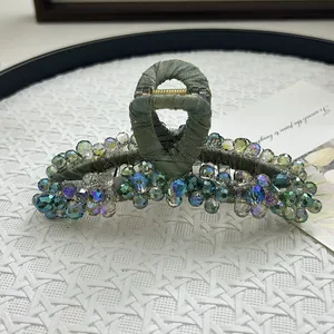 Macro shot of large hair claw clip with colorful crystal beads and grey-green fabric