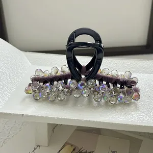 Detailed close-up of large hair claw clip with purple fabric and crystal bead embellishments