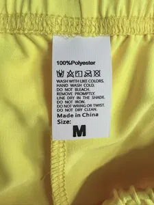 Detail des hochwertigen 100 % Polyestergewebes und Waschetiketts auf gelben Sportshorts