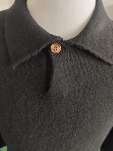 Gedetailleerde close-up van een zwarte gebreide polotrui kraag met een amberen knoop