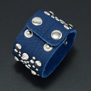 Dettaglio della pelle blu con borchie argentate e strass sul bracciale largo
