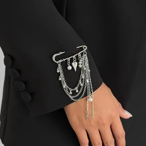 Detail of silver multi-layer safety pin brooch with star and heart charms on black fabric