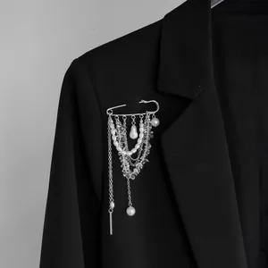 Vue détaillée de la broche épingle argentée avec perles et cristaux sur un blazer noir