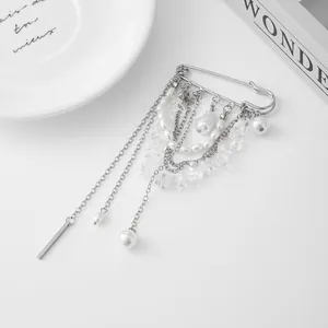 Détail d'une broche épingle de sûreté avec franges de chaînes argentées et perles