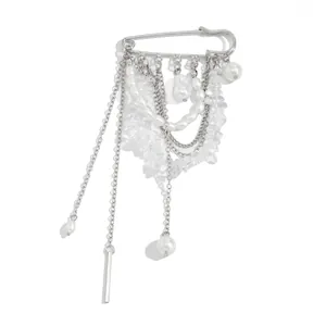Détails d'une broche à pompons argentés avec perles blanches et chaînes étagées
