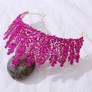 Detail of baroque gold leaf crown featuring vibrant fuchsia crystals and intricate design