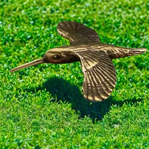 Macro view of flying brass hummingbird sculpture with detailed wings and metallic finish