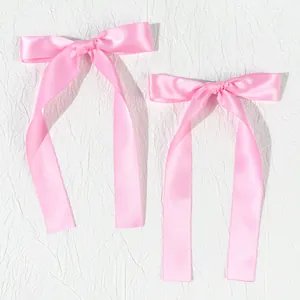 Detail of pink satin bow hair clips with long ribbons and smooth silky texture