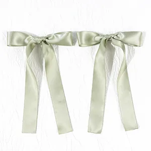 Detail of sage green satin bow hair clips with long ribbons and silky texture finish