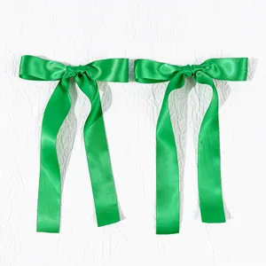 Close-up of bright green satin ribbon hair bows with long streamers and silk texture