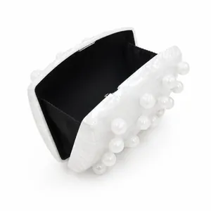 Detail view of pearlescent evening clutch with white pearls and black lining