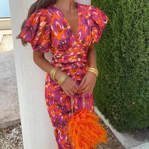 Detail view of V-neckline and orange purple leopard print on a slim pleated dress