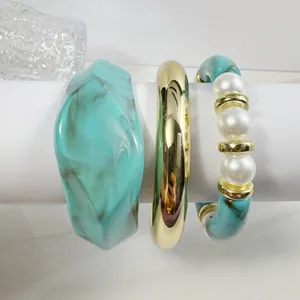 Detailed view of resin marble bangle and beaded bracelet with pearls on a stand