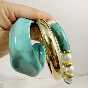 Three-piece set featuring teal resin cuff, gold metal bangle, and beaded pearl bracelet