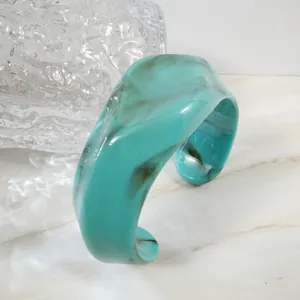 Detail of teal resin cuff bracelet featuring marble texture and a wide open-ended design