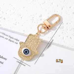 Macro detail of gold Hamsa hand keychain with blue Evil Eye and measurement marks
