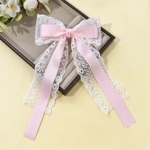 Détail d'un nœud papillon en satin rose avec dentelle florale blanche et longs rubans