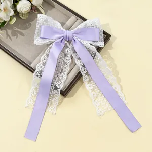 Détail de la pince à cheveux nœud en satin lilas avec des rubans en dentelle florale