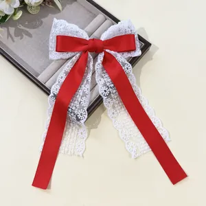 Détail du nœud papillon en satin rouge avec dentelle blanche et longs rubans fins