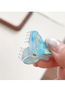 Detailed macro view of a mini blue marbled acetate hair claw clip with golden glitter
