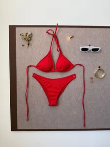 Flat lay of red ribbed bikini set with sunglasses and summer decor on neutral background