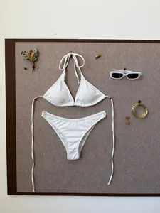 Flat lay of white ribbed two-piece bikini with halter top and sunglasses on a board