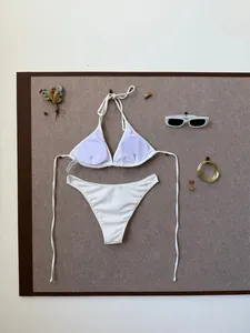 Flat lay of white ribbed bikini set with neck ties and gold vacation accessories