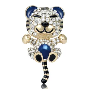 Broche tigre dorée avec strass blancs et perle bleu foncé sur fond blanc épuré
