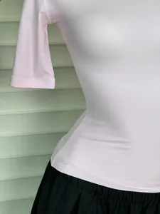Close-up of pink ribbed knit short sleeve top paired with black pleated skirt